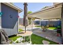 Backyard with patio, a covered seating area, artificial turf, a small shed, and mature desert landscaping at 6924 Senton Ave, Las Vegas, NV 89108