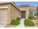 Inviting home entrance featuring manicured landscaping, decorative trim, and a blue front door at 7559 Chambery Cove Ct, Las Vegas, NV 89123