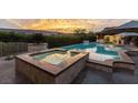 Inviting backyard showcasing a luxurious pool and spa area with mountain views at sunset at 15 Golden Sunray Ln, Las Vegas, NV 89135