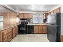 Bright kitchen featuring wood cabinets, granite counters, black appliances and a stainless steel refrigerator at 3471 Cape Cod Dr, Las Vegas, NV 89122