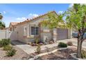 Exterior shot of a well kept house with neutral paint, desert landscaping, and a two car garage at 406 River Glider Ave, North Las Vegas, NV 89084