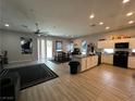 Open concept showcasing a large kitchen area and living room with stainless steel appliances, dark furniture, and tile floors at 6450 Cinnamon Hazlenut St, North Las Vegas, NV 89084