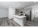 A modern kitchen with stainless steel appliances, gray cabinets, a large island, and hardwood floors at 817 Cottonwood Hill Pl, Henderson, NV 89011