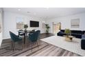 This living room with a dining area has dark hardwood floors, a large screen TV, and a sliding glass door to the backyard at 817 Cottonwood Hill Pl, Henderson, NV 89011