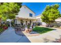 A backyard patio area with dining set, lush lawn, mature landscaping, and mature trees at 10413 Rising Harbor Ave, Las Vegas, NV 89129