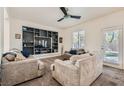 Inviting living room featuring neutral paint, carpet, ceiling fan and custom built-in shelving unit at 10413 Rising Harbor Ave, Las Vegas, NV 89129