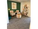 Comfortable sitting area featuring neutral-toned chairs, a woven ottoman, and stylish shelving against a green accent wall at 1900 Arietta Vista St, Henderson, NV 89044