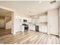 Modern kitchen featuring stainless steel appliances, white cabinets, and stylish wood-look flooring at 4118 Beech Family St, Las Vegas, NV 89115