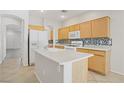 Functional kitchen boasts light wood cabinets, white appliances, and a mosaic backsplash at 5240 Adorato Dr, North Las Vegas, NV 89031