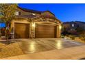 Three-car garage with stone accents, brown doors, and wide driveway surrounded by landscaped front yard at 7311 Spring Flower Ave, Las Vegas, NV 89117