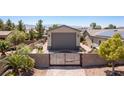 View of the property showcasing the private gate, brick accents, and desert landscaping at 8713 Long Winter Ct, Las Vegas, NV 89131