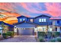 Inviting two-story home with a well-maintained yard, stone accents, and a two-car garage set against a vibrant sunset sky at 2714 Frabiele St, Henderson, NV 89044