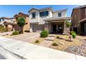 Inviting two-story home showcasing a paved driveway, stone-accented columns, and attractive desert landscaping at 1034 Fish Pond Ave, Henderson, NV 89014