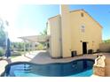 Spacious backyard featuring a covered patio, private pool, lush landscaping, and a pristine lawn at 2140 Desert Peak Rd, Las Vegas, NV 89134