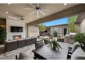 Covered outdoor living area with a fireplace, ceiling fans, tv, and built in BBQ and patio set at 6804 Regency Stone Way, Las Vegas, NV 89148