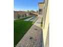 Backyard with artificial turf, stone pavers, rock landscaping, and brick perimeter wall at 6834 Compass St, North Las Vegas, NV 89084