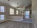 Bright living room featuring light wood floors, staircase, and ample natural light from large windows at 9556 Ancala Hollow Ct, Las Vegas, NV 89148