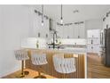 Modern kitchen with white cabinets, quartz countertops, wood floors, and stylish barstool seating at the island at 9900 Summer Ash Ct # 103, Las Vegas, NV 89134