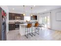 Modern kitchen with stainless steel appliances, sleek dark cabinetry, breakfast bar and a adjacent dining area at 10434 Rose Palisade St, Las Vegas, NV 89141