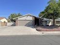 Inviting single-story home featuring a two-car garage and lush landscaping and rock groundcover at 1441 Bronco Rd, Boulder City, NV 89005