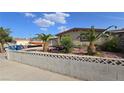 A charming one-story house is surrounded by low-maintenance desert landscaping and a privacy wall at 5209 Del Monte Ave, Las Vegas, NV 89146