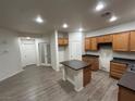 Spacious kitchen featuring a center island, wood cabinets, and wood-look floors with ample storage space at 6412 Point Break St, North Las Vegas, NV 89084