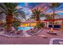 Exterior backyard view featuring a firepit, pool, and desert landscaping, enhanced by dramatic sunset skies at 1561 Doran Dr, Las Vegas, NV 89123