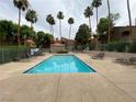 Community pool with lounge chairs surrounded by lush greenery and palm trees, offering a refreshing outdoor space at 220 Mission Catalina Ln # 203, Las Vegas, NV 89107
