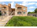 Two-story building with stucco finish, stairs leading to upper units, and lush green landscaping at 221 Mission Catalina Ln # 104, Las Vegas, NV 89107