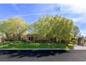 Stunning home exterior featuring mature trees, manicured landscaping, and a well-maintained lawn creating great curb appeal at 33 Promontory Ridge Dr, Las Vegas, NV 89135