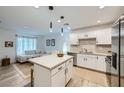 Open-concept kitchen with white cabinets, stainless steel appliances, island, and view into the cozy living room at 709 Pickled Pepper Pl, Henderson, NV 89011