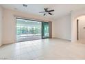 Open living area with tile flooring, ceiling fan, and large sliding doors to the outdoor patio at 8732 Kendall Brook Cir, Las Vegas, NV 89149