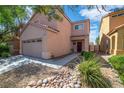 Two-story home showcasing a two-car garage, complemented by rock landscaping and blue skies at 9031 Jumping Jacks Ave, Las Vegas, NV 89178