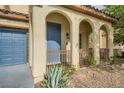 Covered home entry with decorative arches and blue door, adjacent to the two-car garage at 10428 Mulvaney Cir, Las Vegas, NV 89141