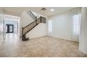 Bright, tiled living room featuring a staircase and large windows with sheer, white curtains at 10428 Mulvaney Cir, Las Vegas, NV 89141