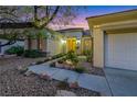 Evening shot of a landscaped front yard with a stone walkway leading to a beautifully lit home entrance at 1637 Wellington Springs Ave, Henderson, NV 89052
