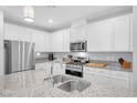 Bright kitchen with white cabinets, stainless appliances, granite counters, and a double basin sink at 2404 Elmont Ave, North Las Vegas, NV 89086