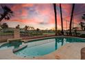 Backyard oasis featuring a sparkling pool with surrounding palm trees and a privacy fence at 2496 Ram Crossing Way, Henderson, NV 89074
