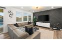 Living room features a leather sectional couch, accent wall, large windows, and decorative art pieces at 2833 Sangro Ct, Henderson, NV 89044