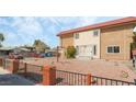 View of a two-story tan building with a red tile roof, desert landscaping and black metal fencing at 2915 Cedar Ave # 11C, Las Vegas, NV 89101