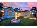 Backyard view highlighting a fire pit with flames, manicured artificial turf, and desert landscaping at 5509 Rose Thicket St, Las Vegas, NV 89130