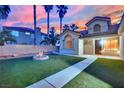 Cozy backyard features a fire pit, green artificial turf, and palm trees against a colorful sunset at 5509 Rose Thicket St, Las Vegas, NV 89130