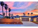 House with a two-car garage, desert landscaping, and palm trees, against a colorful sunset backdrop at 5509 Rose Thicket St, Las Vegas, NV 89130