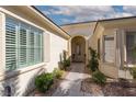 Inviting front entrance with an arched doorway, desert landscaping and shuttered windows at 10240 Notte Ave, Las Vegas, NV 89135