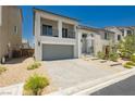 Charming two-story home featuring a balcony, gray-tone stucco, a paver driveway, and minimalist desert landscaping at 10429 Rose Palisade St, Las Vegas, NV 89141