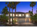 Elegant two-story home at dusk featuring a three-car garage, palm trees, and a well-manicured front yard at 11056 Kilkerran Ct, Las Vegas, NV 89141