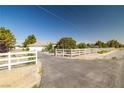 Property featuring a long white fence, an ample driveway, and mature trees dotting the landscape at 170 Dove St, Pahrump, NV 89060