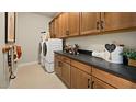 Well-organized laundry room with upper and lower cabinets, a washer, and a dryer at 227 Paraggi Bay Dr, Henderson, NV 89011