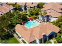 Aerial shot of a community pool with red umbrellas, surrounded by lush landscaping and multiple buildings at 45 Maleena Mesa St # 223, Henderson, NV 89074