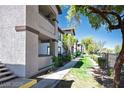 An exterior side view of a condo building with stucco walls and a walking path lined with greenery at 45 Maleena Mesa St # 223, Henderson, NV 89074